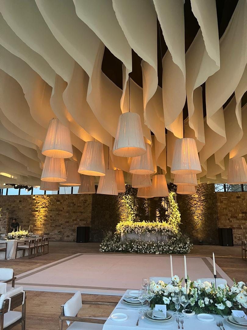 Draped fabric ceiling with pleated lanterns over a dance floor and white florals