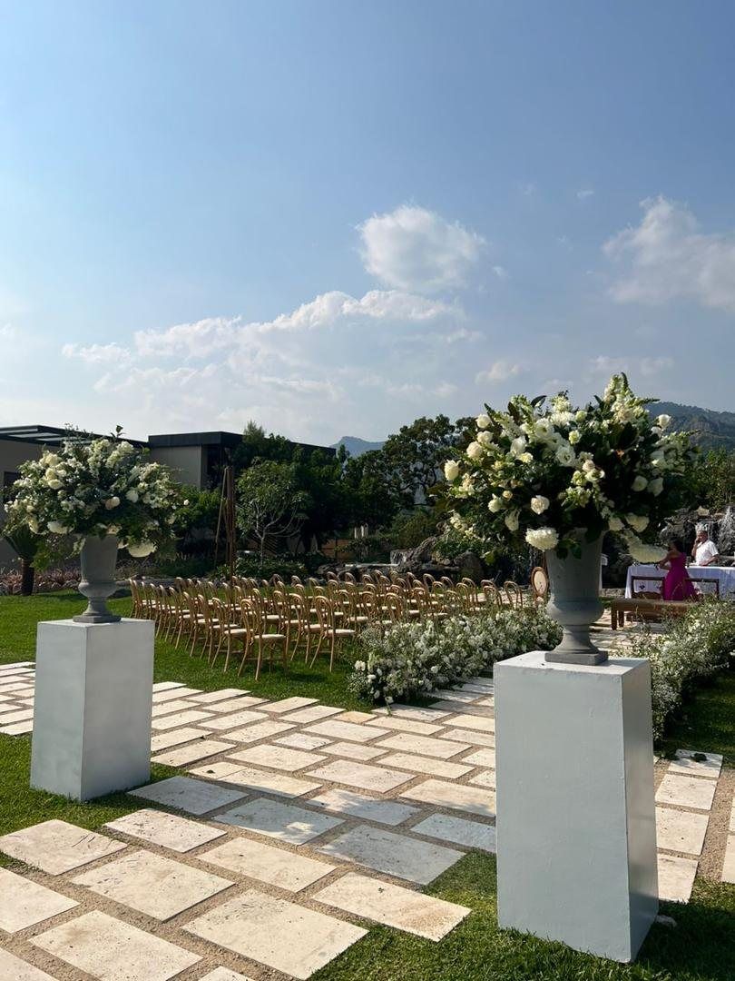 Ceremony aisle with white urns, bentwood chairs and mountains beyond