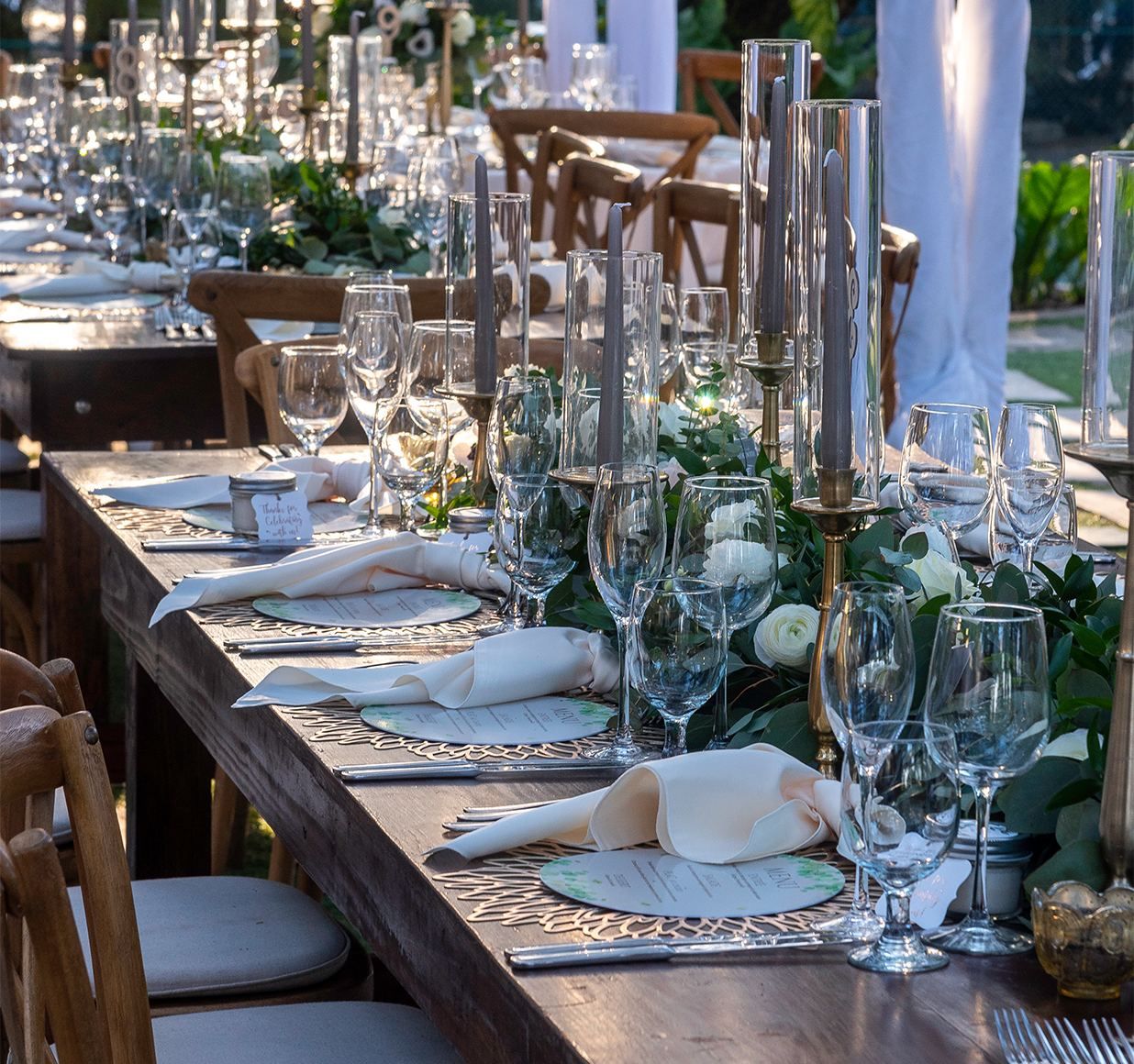 Long wooden table set with candlesticks, glassware and white drapery
