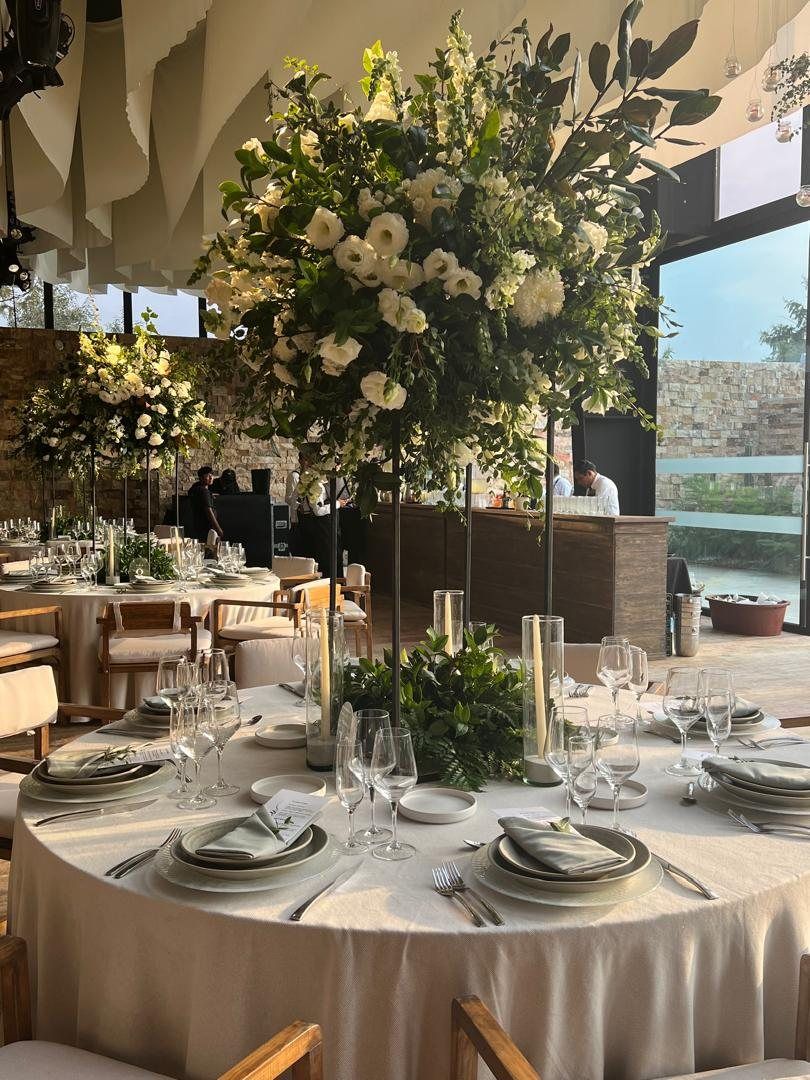 Tall white floral centrepiece over a round table in sage and linen