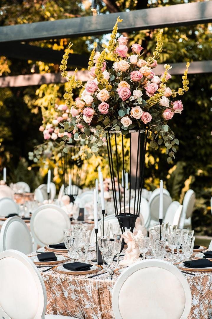 Tall arrangement of pink roses over a table with black candles and crystal