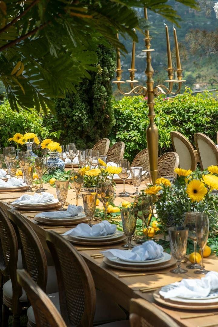 Garden table with yellow gerberas, lemons and gold candelabra